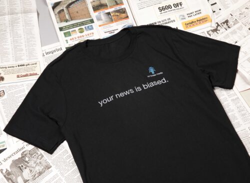 your news is biased shirt on top of newspapers