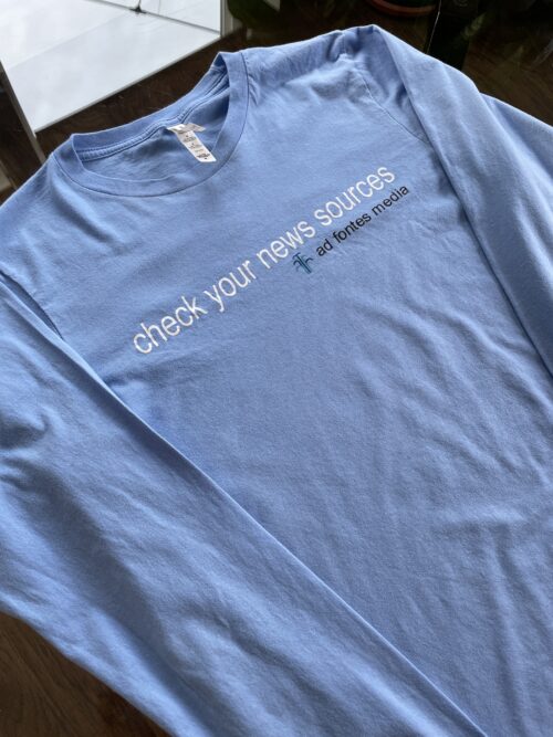 Carolina blue long-sleeved T-shirt with "Check Your News Sources," and the Ad Fontes logo.